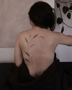 the back of a woman's body with leaves painted on her upper and lower back