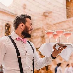 a man holding a tray with wine glasses on it