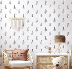 a teddy bear sitting in front of a white wall with black and white trees on it