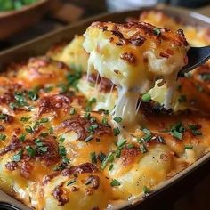 a close up of a casserole with cheese and green onions being lifted from the casserole