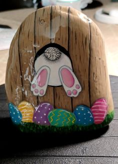 an easter decoration with painted eggs in front of a wooden door and bunny ears on it