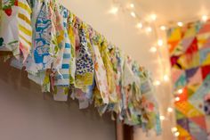 several colorful pieces of cloth hanging on a wall next to a bed with lights in the background