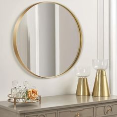 a table with a mirror and vases on it next to a gold candle holder