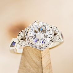 a diamond ring on top of a wooden stand