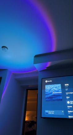 a flat screen tv mounted to the side of a wall next to a blue ceiling