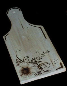 a wooden cutting board with floral designs on the bottom and one flower in the middle