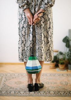 a woman standing on top of a rug holding an object in one hand and wearing black shoes