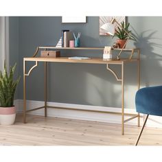 a desk with a blue chair next to it and a plant on the side table