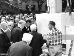 a group of men standing around each other in front of a building and looking at something