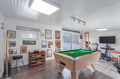 a room with a pool table, exercise equipment and pictures on the wall