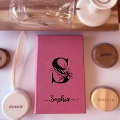 a pink book sitting on top of a table next to some cups and spoons