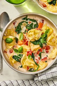 two bowls filled with pasta and spinach on top of a table