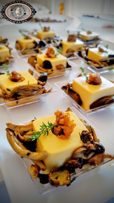 several desserts are arranged in small square dishes on a white tablecloth with an ornate border around the edges