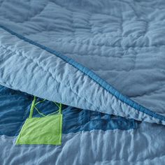 two blue and green bedspreads laying on top of each other