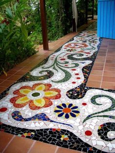 several pictures of different designs and colors on the floor in front of a building with plants