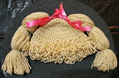 a crocheted hat with pink ribbon on the top and two tassels attached to it