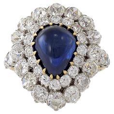 This Estate piece from the Victorian Era is set in 18KT yellow gold and platinum featuring a Blue Sapphire and diamonds. A cocktail ring consisting of one pear shaped cabochon genuine blue sapphire weighing 8.50CT surrounded by 5.30CT-TW old European cut diamonds. The beautiful sapphire and diamonds in this Estate piece from the Victorian Era combine to create a stunning cocktail ring, made with the highest quality 18KT yellow gold and platinum. Sapphire And Diamond Ring, Sapphire Diamond Ring, European Cut Diamonds, Sapphire Diamond, Gold Platinum, Cocktail Ring, Victorian Era, Cocktail Rings, Pear Shaped