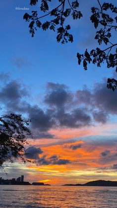 the sun is setting over the water and trees