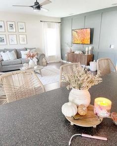 a living room filled with furniture next to a dining room table and chair covered in pillows