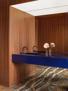 a blue counter with two vases on it in front of a wooden cabinet and sink