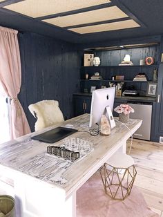 a desk with a computer on top of it in a room that has blue walls and wooden floors