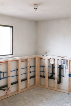 an unfinished room with pipes in the wall and plumbing on the floor, along with windows