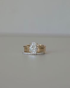 two gold wedding rings with a single diamond on each one and side stones in the middle