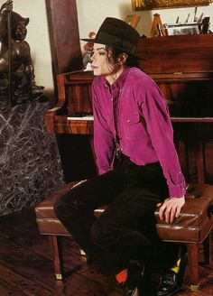 a man sitting on top of a stool next to a piano