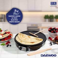 an electric crepe maker with strawberries and raspberries on the counter