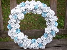 a wreath made out of pine cones sitting on top of a wooden bench