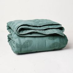 two blankets folded on top of each other in front of a white wall and floor