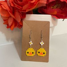 a pair of earrings with an image of a pacman on the front, and a flower in the back