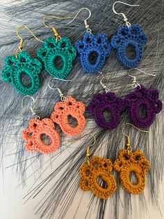 four crocheted earrings are shown in different colors