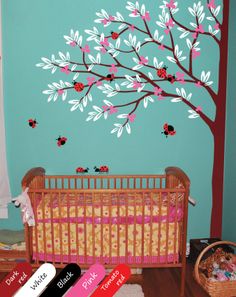 a baby's room with a tree and ladybugs painted on the wall