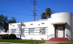 a white building with red steps and palm trees in the background