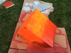 an orange object sitting on top of a piece of cardboard next to other pieces of paper