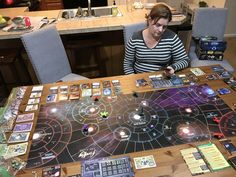 a woman sitting at a table with a board game set up on top of it