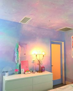 a bedroom with blue and pink walls, white dressers and pictures on the wall