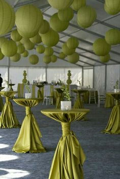 tables and chairs covered in yellow cloths with paper lanterns hanging from the ceiling above them