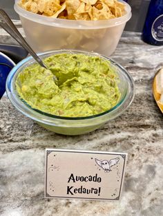 guacamole and tortilla chips are served in bowls on the counter