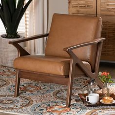 a brown leather chair sitting on top of a rug next to a potted plant