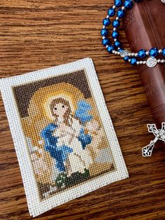 a cross and rosary sitting on top of a wooden table next to a beaded bracelet