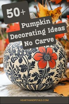 a pumpkin decorated with black and white flowers is sitting in front of some fall leaves