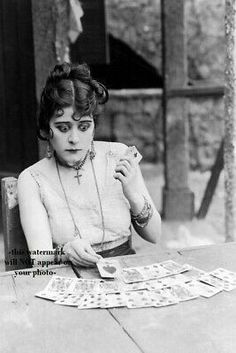 an old photo of a woman sitting at a table with cards in front of her