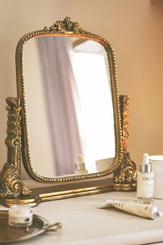 a mirror sitting on top of a table next to a bottle of lotion and a brush