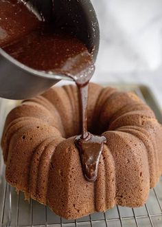 a bundt cake with chocolate icing being drizzled over it on a cooling rack