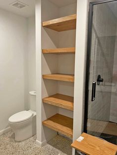 a bathroom with a toilet, shower and shelving unit in the middle of it