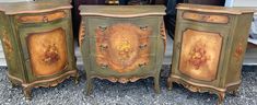 two green and gold painted chests sitting next to each other on top of gravel covered ground