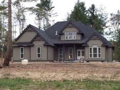 a large gray house sitting in the middle of a forest