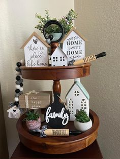 a three tiered tray with small houses on it and some plants in the middle